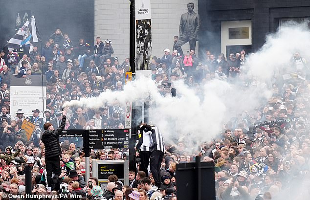 Smoke trails from a flair as jubilant Newcastle fans mass outside the club's ground in celebratory mood