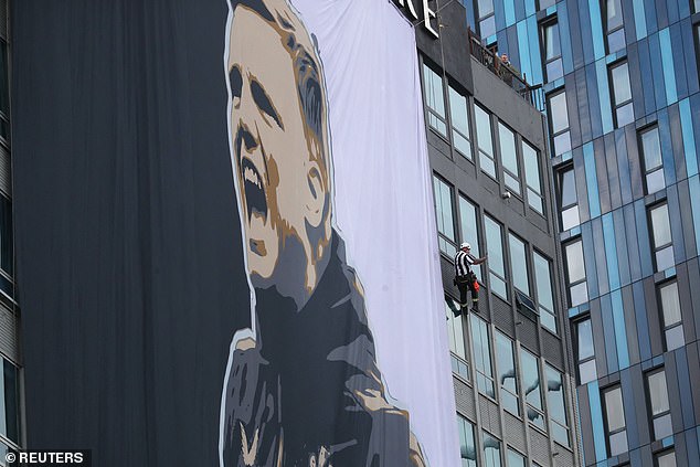 A worker in a Newcastle United jersey next to a gigantic banner of victorious Newcastle manager Eddie Howe