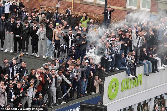 Newcastle fans take to the roofs of shops to get a good view of the open top bus as it passes