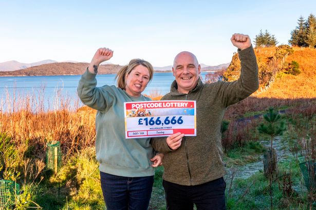 Charlie and Ian with the winning cheque in picturesque Scotland, where they now live