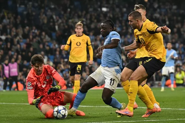 Dortmund's Swiss goalkeeper Gregor Kobel (L) saves from the feet of Manchester City's Belgian midfielder Jeremy Doku during the UEFA Champions League football match between Manchester City and Borussia Dortmund