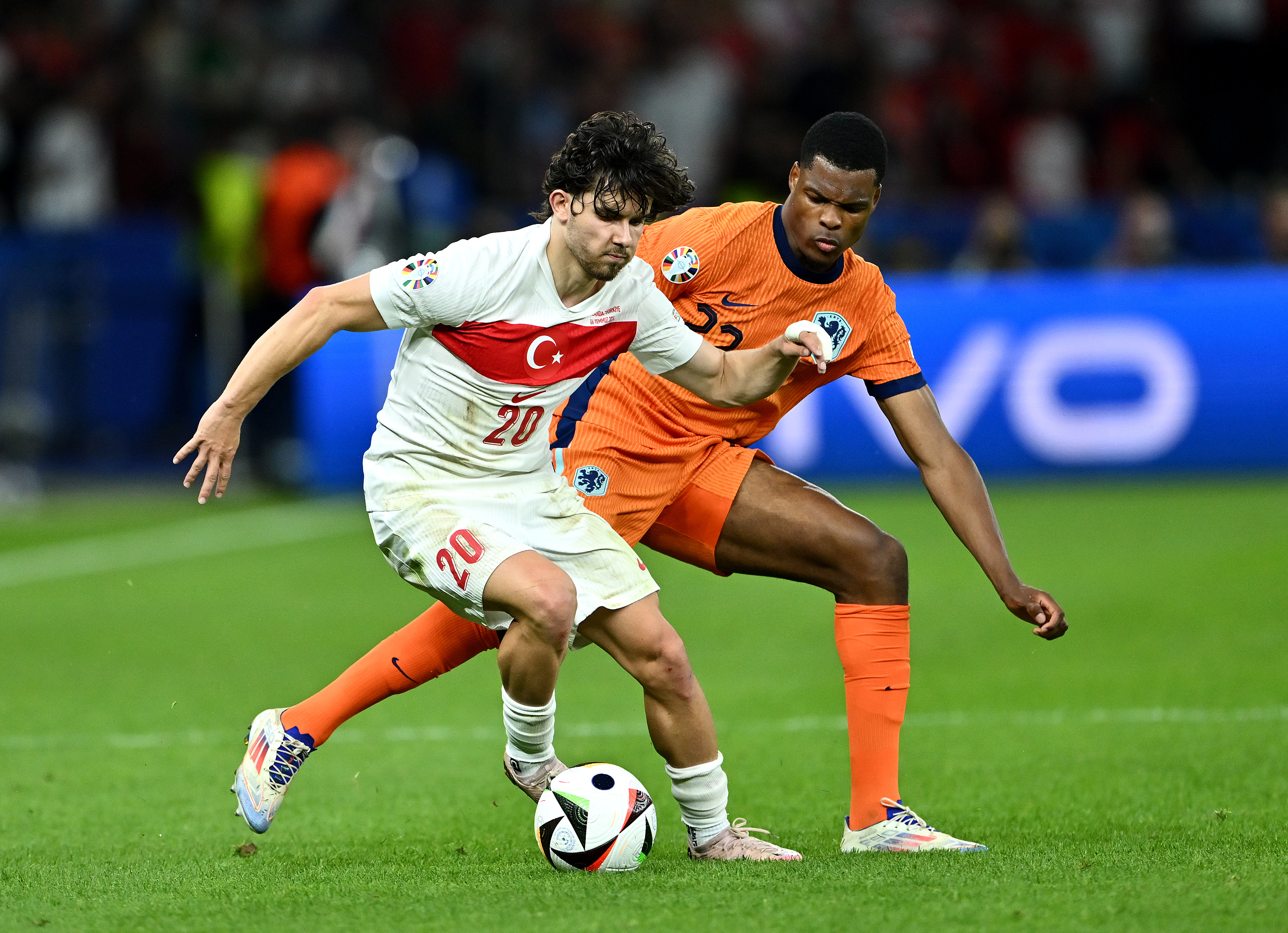 Ferdi Kadioglu of Turkiye controls the ball under pressure from Denzel Dumfries of the Netherlands during a UEFA EURO 2024 quarter-final match.