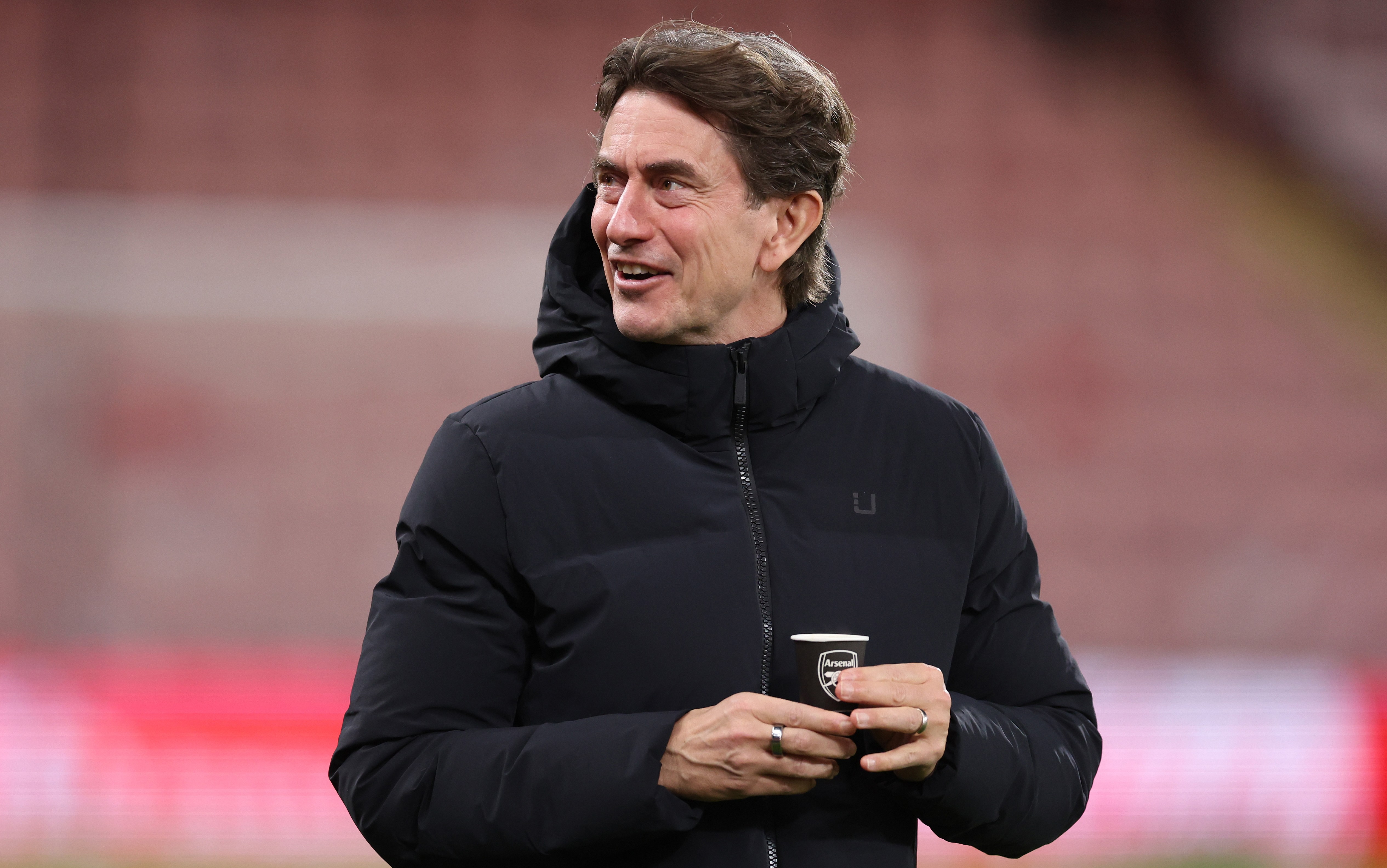Thomas Frank, Tottenham Hotspur's manager, holding a cup with the Arsenal club badge.