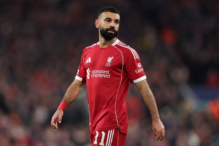 Mo Salah Mo Salah, in red Liverpool football kit, walks, watching play, on the pitch at Anfield.