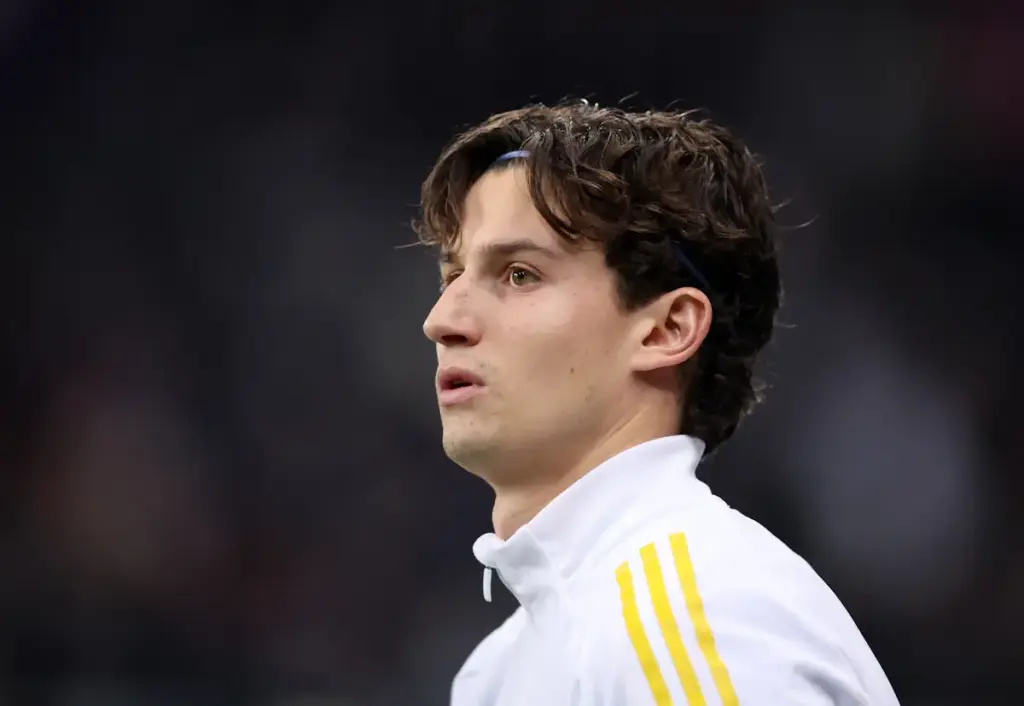Leeds United star Brenden Aaronson looks on before a match, wearing his tracksuit