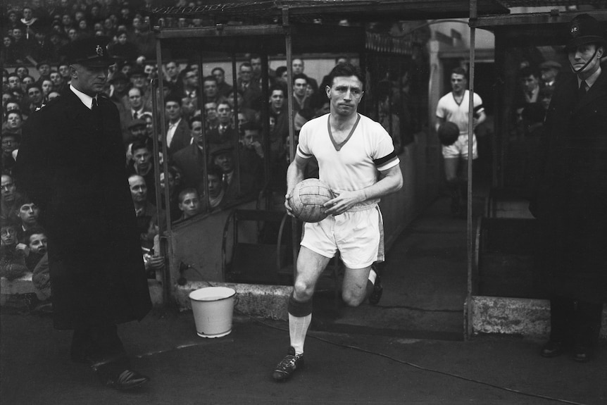 Roger Byrne holds a ball and runs out of a tunnel