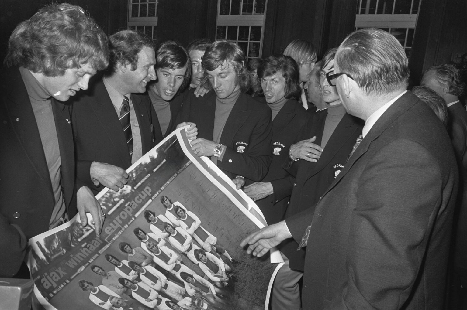 AFC Ajax players surround a poster in tribute to their 1971–72 European Cup win. (1972) [3671×2441]