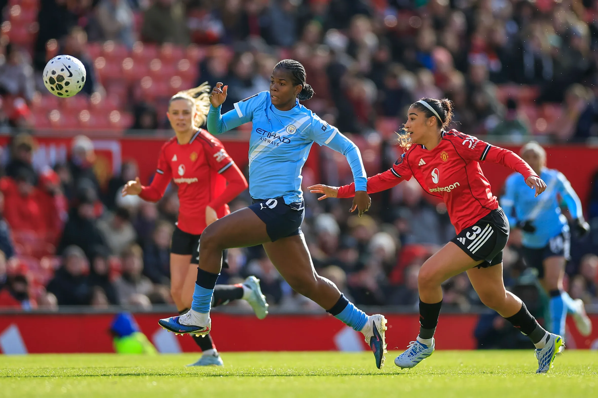 Khadija Shaw of Manchester City runs with the ball under challenge from Gabrielle George of Manchester United.