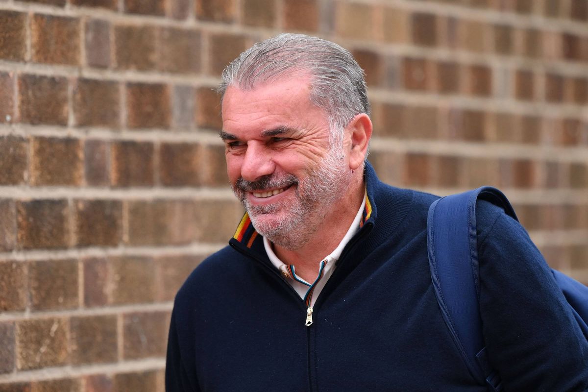 Ange Postecoglou stood in front of a wall, smiling
