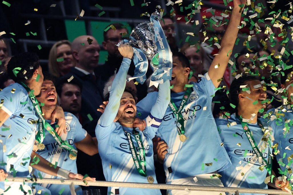 Manchester City's Portuguese midfielder #20 Bernardo Silva lifts the trophy as City players celebrate after the English League Cup final football match between Arsenal and Manchester City at Wembley Stadium in London on March 22, 2026. City won the game 2-0. (Photo by Adrian Dennis/AFP via Getty Images) / RESTRICTED TO EDITORIAL USE. No use with unauthorized audio, video, data, fixture lists, club/league logos or 'live' services. Online in-match use limited to 120 images. An additional 40 images may be used in extra time. No video emulation. Social media in-match use limited to 120 images. An additional 40 images may be used in extra time. No use in betting publications, games or single club/league/player publications.