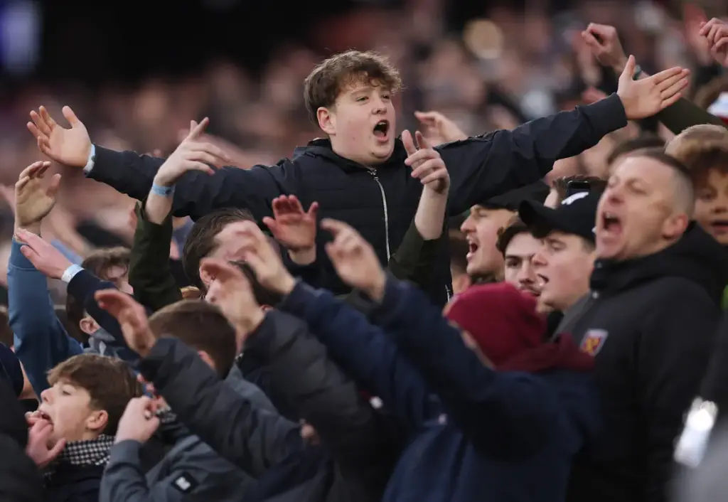 West Ham fans raise their arms and sing to back the team