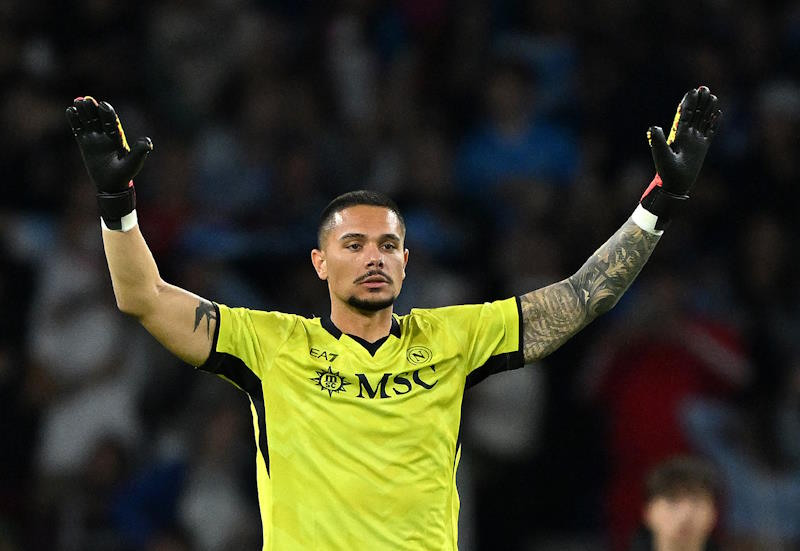 Elia Caprile raises both arms in the air to signal his team-mates while in goal for Napoli