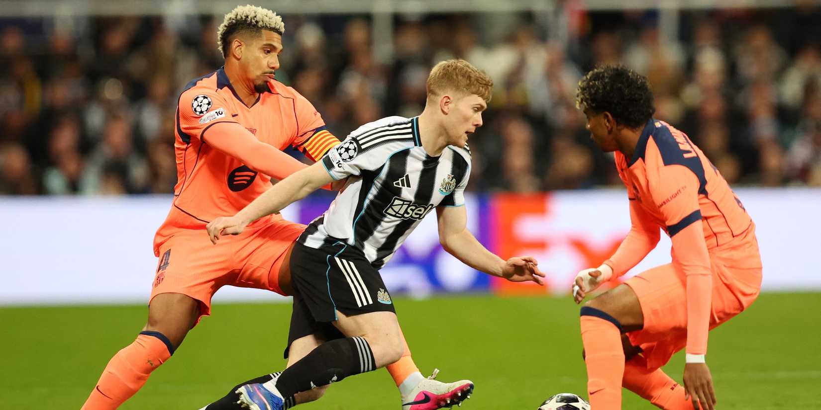 Newcastle United's Lewis Hall in action with FC Barcelona's Ronald Araujo and Lamine Yamal 