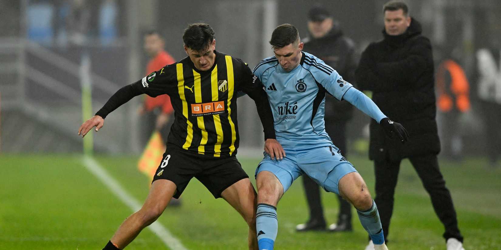 BK Hacken's Silas Andersen in action with Slovan Bratislava's Danylo Ignatenko as BK Hacken coach Jens Gustafsson looks on