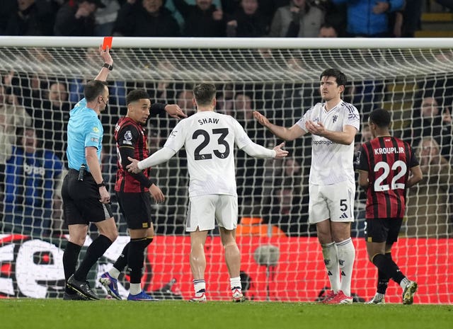 Stuart Attwell, left, shows Harry Maguire a red card