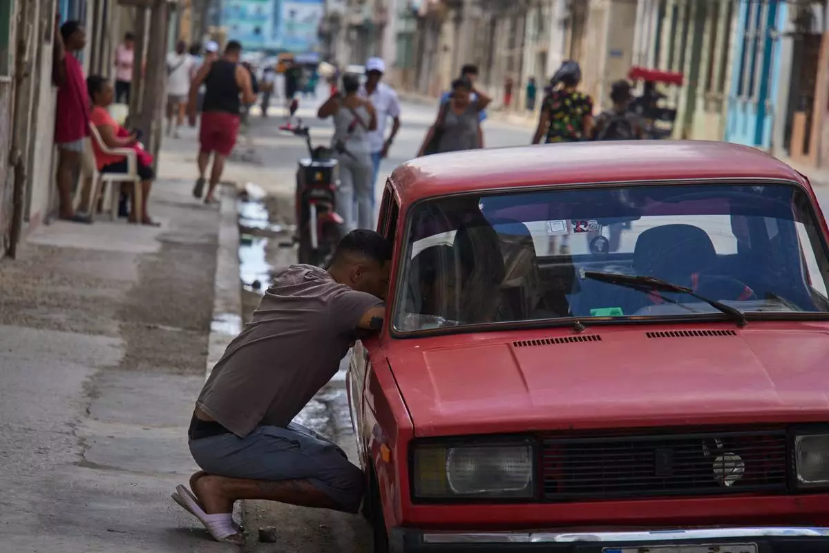 A man speaks with a person in a car during a blackout in Havana, Cuba, Monday, March 16, 2026. (AP Photo/Ramon Espinosa)