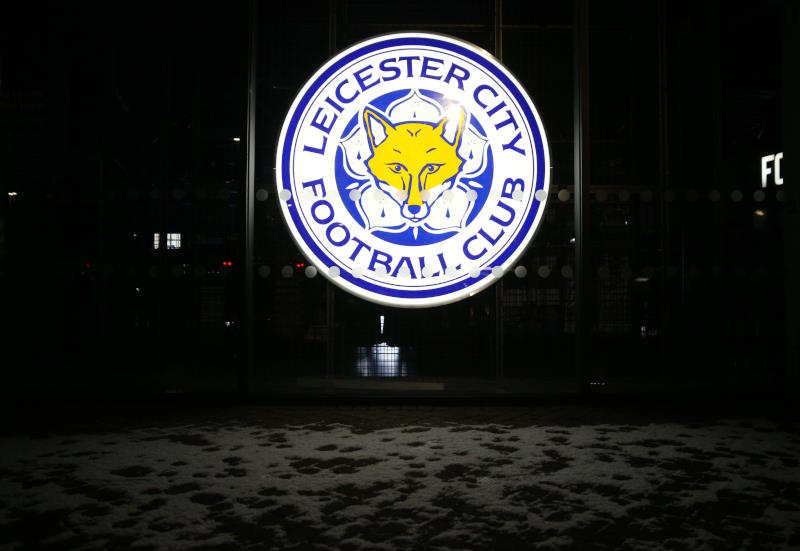 Leicester City's badge is seen lit up in the dark at the club amid snow on the ground in front of it