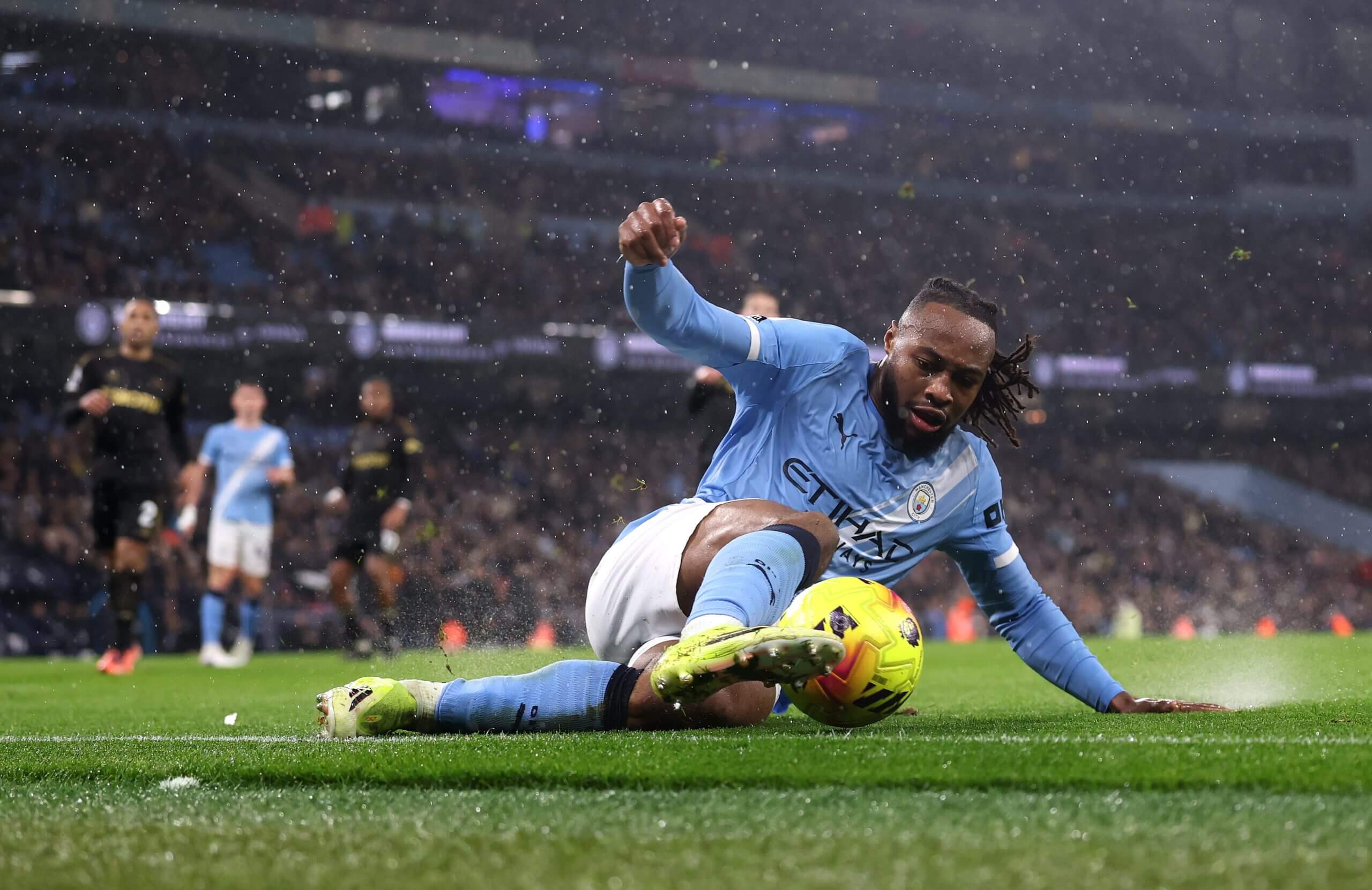 Antoine Semenyo of Manchester City controls the ball woth is left foot while sliding on the wet turf