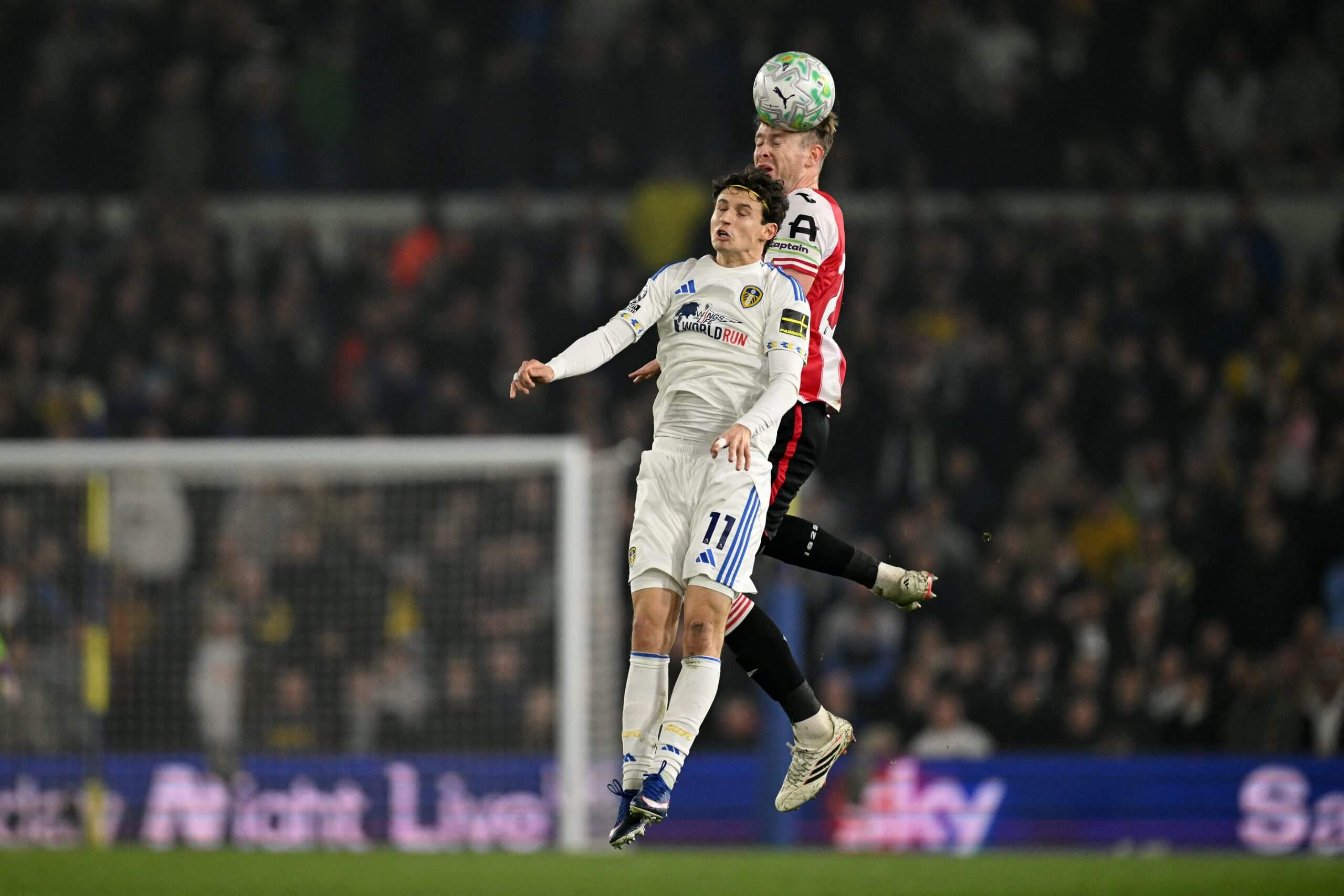 Leeds United's Brenden Aaronson jumps to head the ball with Brentford's Nathan Collins 