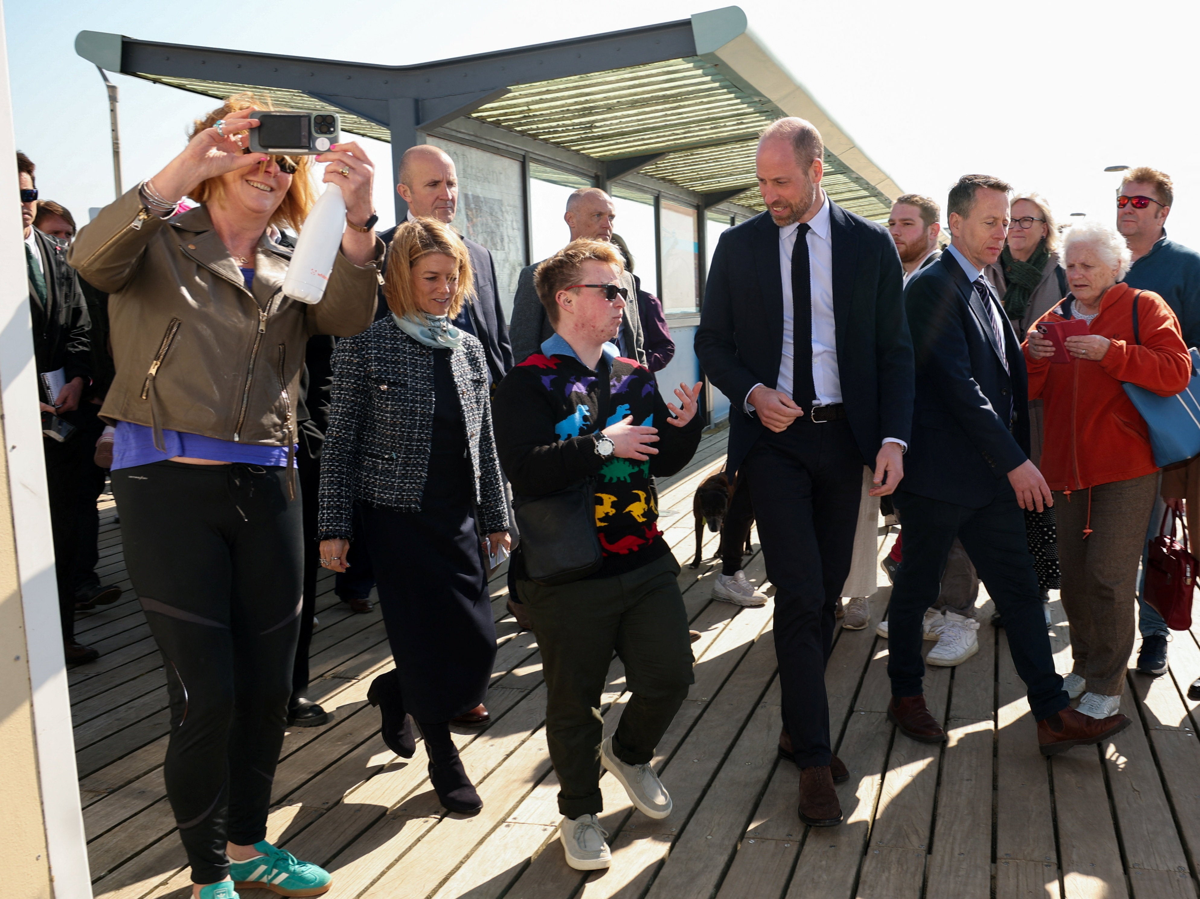 The Prince of Wales walks with Theo from Homewards' National Co-Production Group and Hazel Detsiny, executive director of Homewards, during a visit to see Homewards' ground-breaking youth homelessness work at Bournemouth Pier