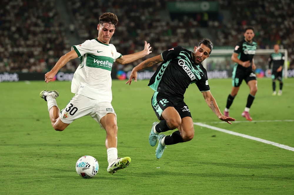 ELCHE, SPAIN: Rodrigo Mendoza of Elche CF crosses the ball whilst under pressure from Ricardo Rodriguez of Real Betis during the LaLiga EA Sports match between Elche CF and Real Betis Balompie at Estadio Manuel Martinez Valero on August 18, 2025. (Photo by Clive Brunskill/Getty Images)