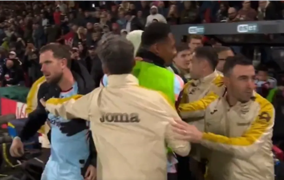 Jordan Henderson is held back by Brentford staff members