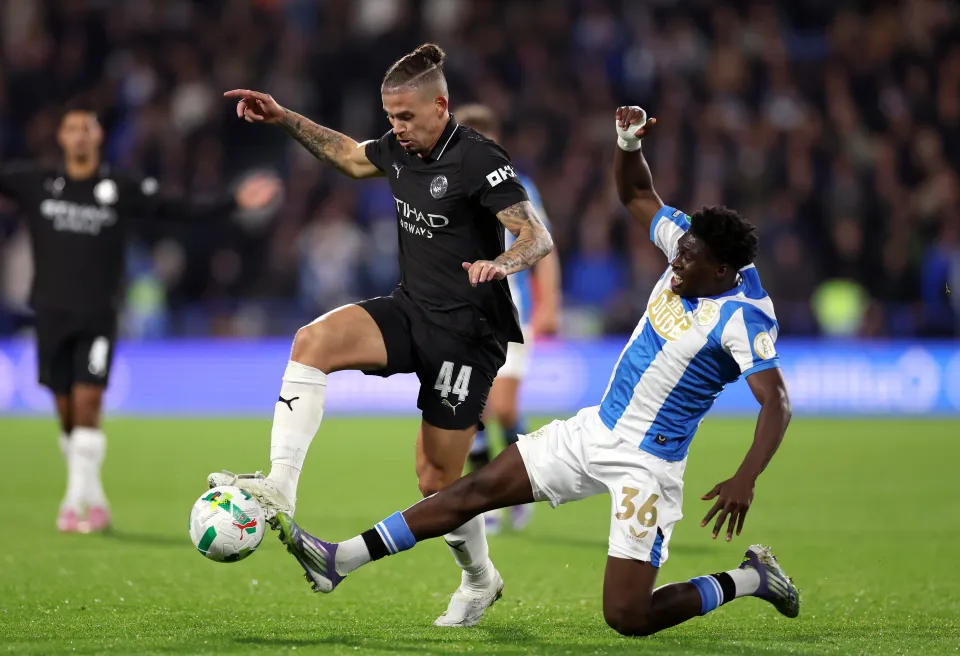 Kalvin Phillips of Manchester City is challenged by Cameron Ashia of Huddersfield Town during the Carabao Cup Third Round match between Huddersfield Town and Manchester City