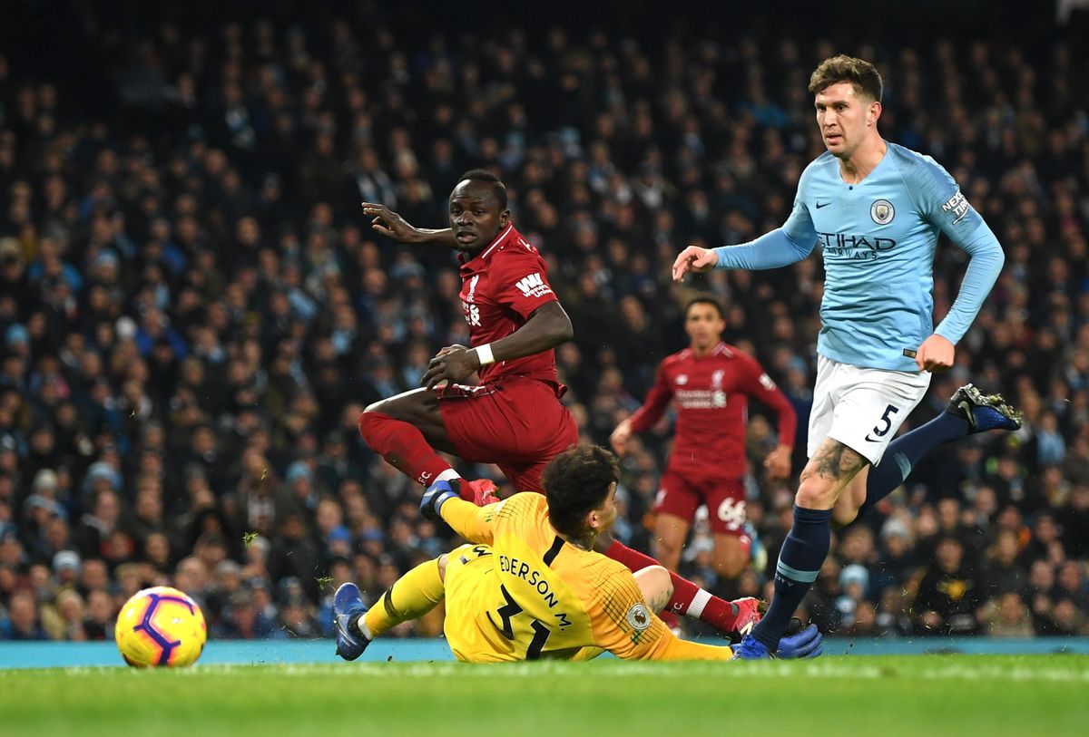 MANCHESTER, ENGLAND - JANUARY 03: Sadio Mane of Liverpool shoots past Ederson of Manchester City as John Stones of Manchester City looks on during the Premier League match between Manchester City and Liverpool FC at the Etihad Stadium on January 3, 2019 in Manchester, United Kingdom.  (Photo by Shaun Botterill/Getty Images)
