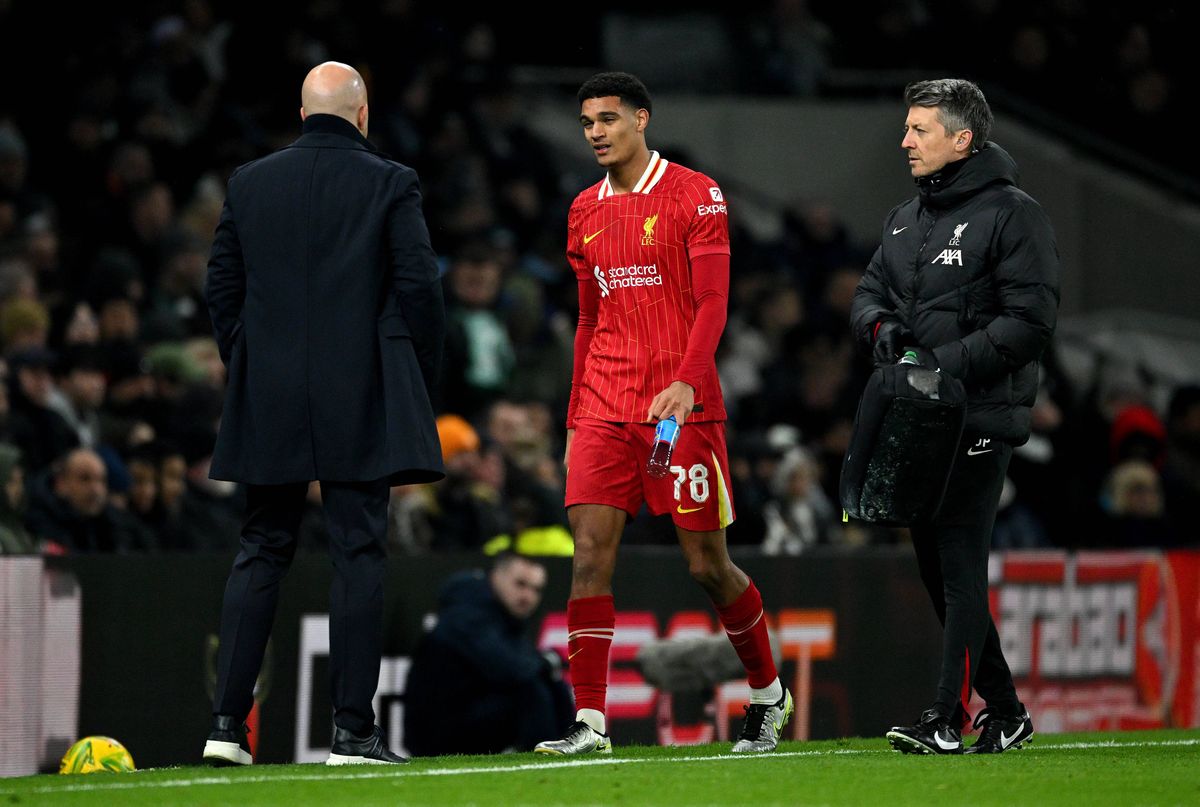 Jarell Quansah of Liverpool speaks to Arne Slot, Manager of Liverpool, as he is substituted due to injury during the Carabao Cup Semi Final First Leg match between Tottenham Hotspur and Liverpool at Tottenham Hotspur Stadium