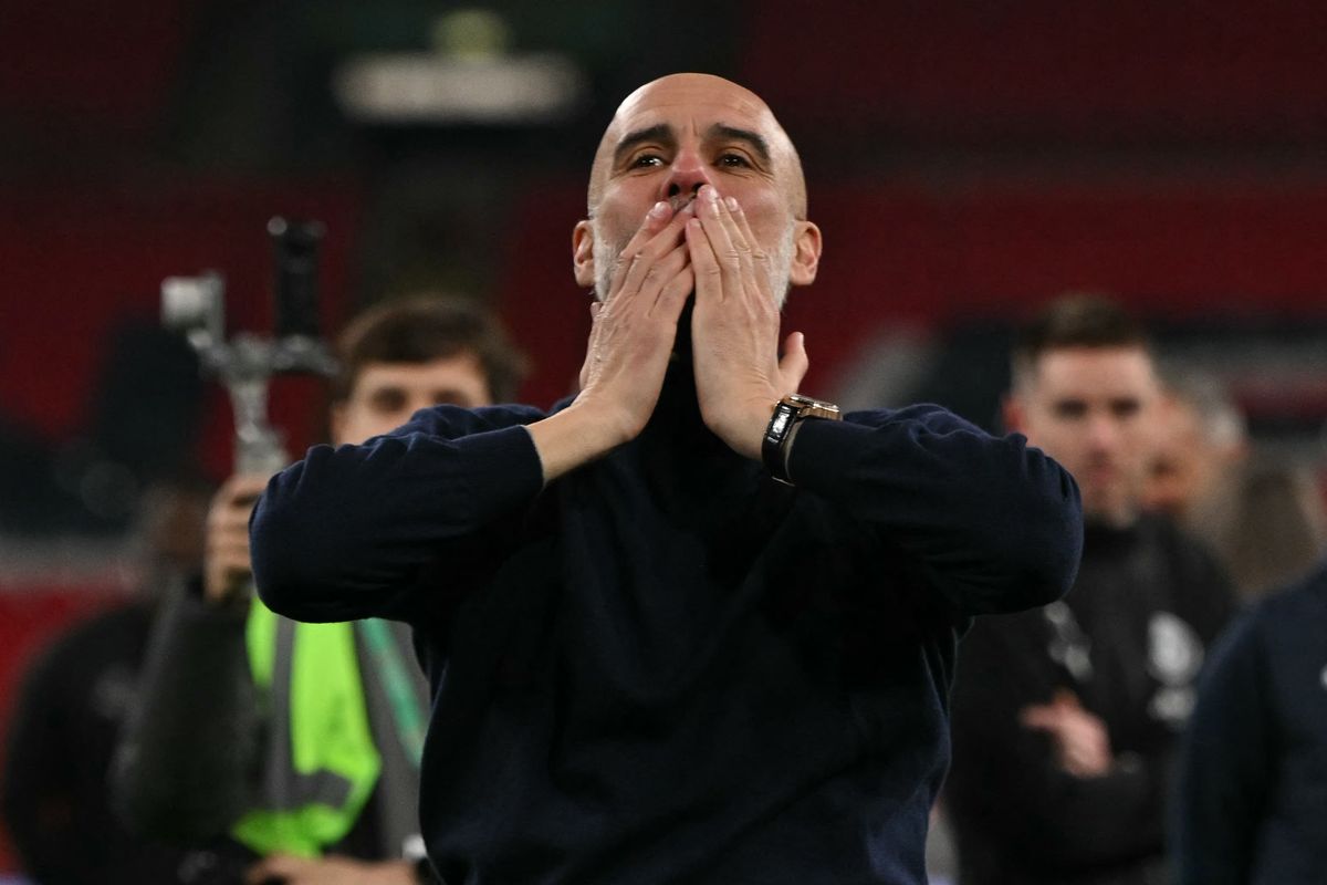 Manchester City's manager Pep Guardiola blows kisses to the fans as City players celebrate after the English League Cup final football match between Arsenal and Manchester City at Wembley Stadium 