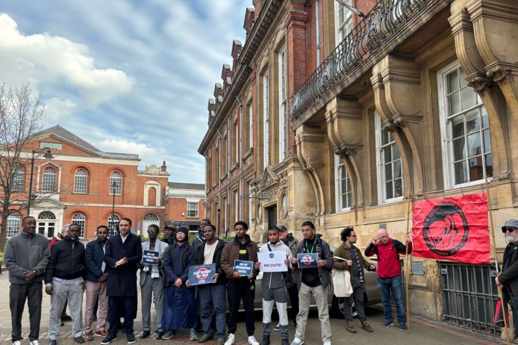 Zakariya Islam (pictured with "no cuts" sign) outside the Town Hall, Leicester.