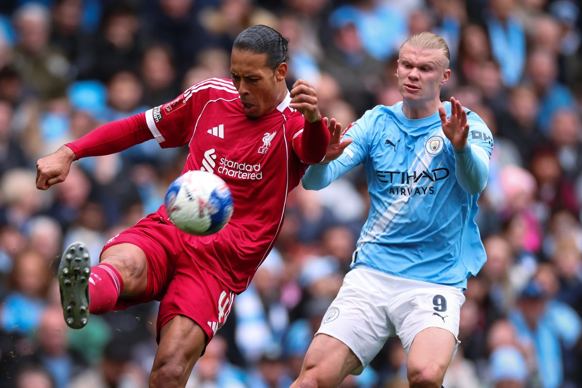 Virgil van Dijk of Liverpool clears the ball under pressure from Erling Haaland