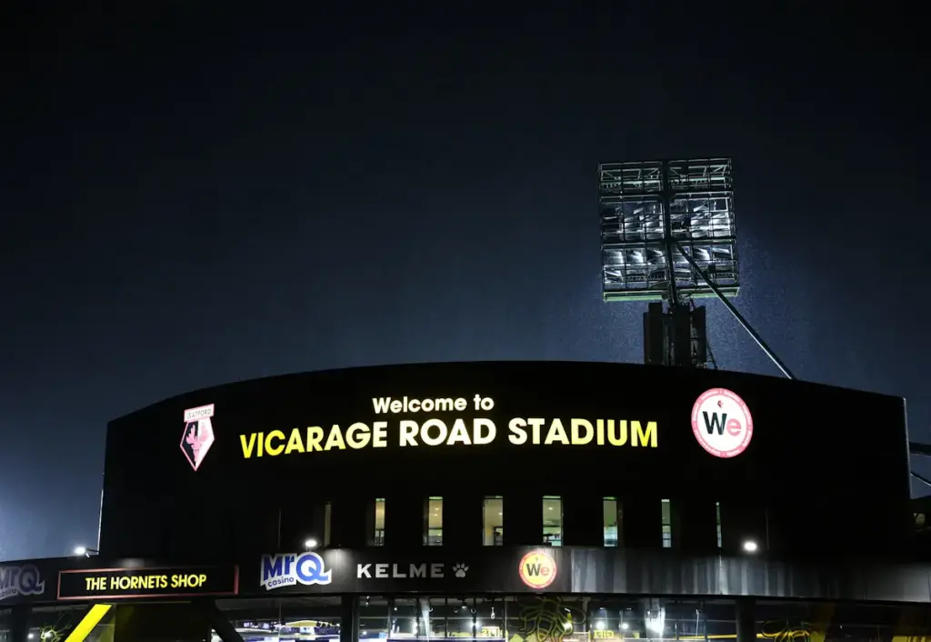 Watford's Vicarage Road stadium seen at night and with a floodlight shining