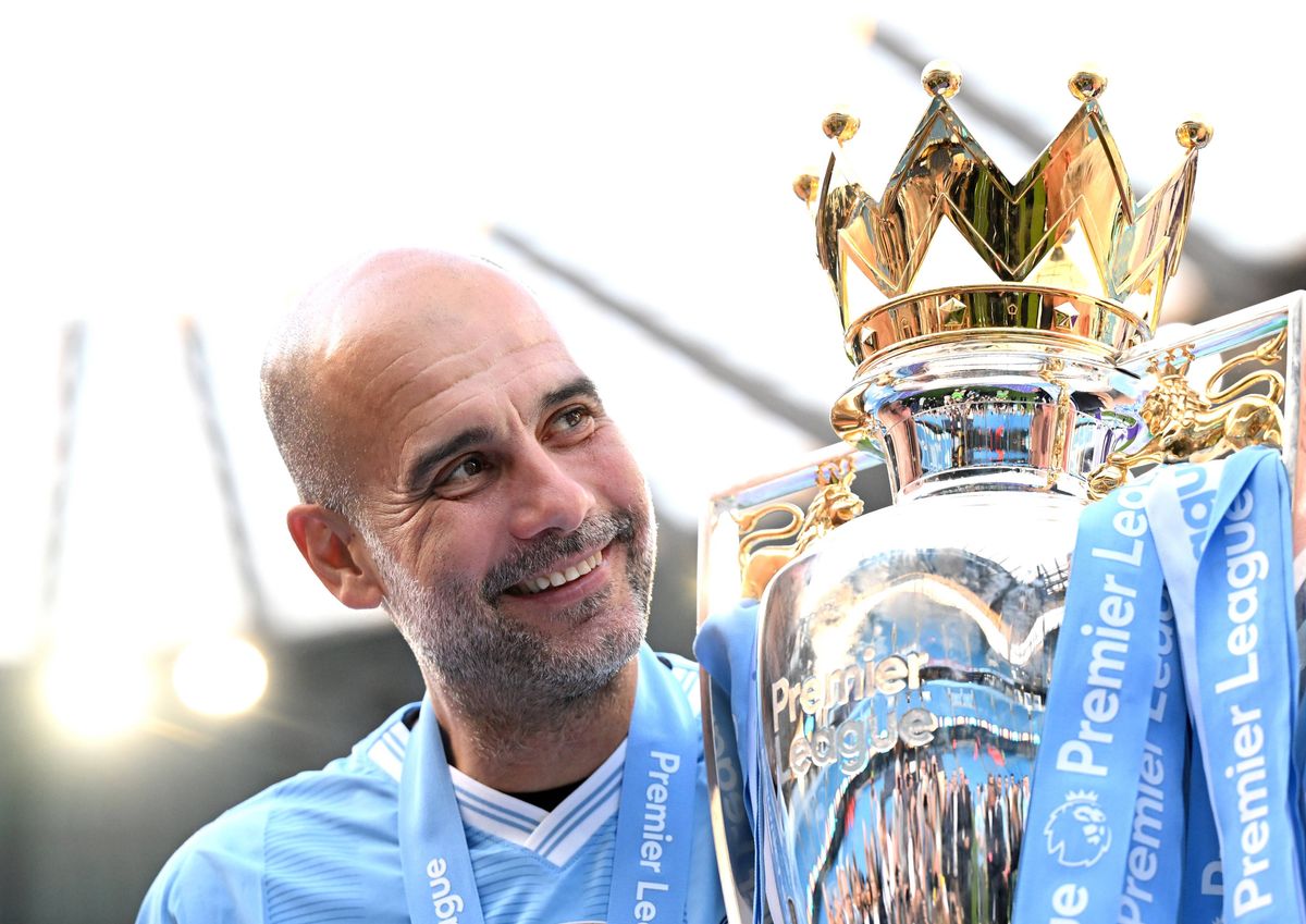 Pep Guardiola poses with the Premier League trophy