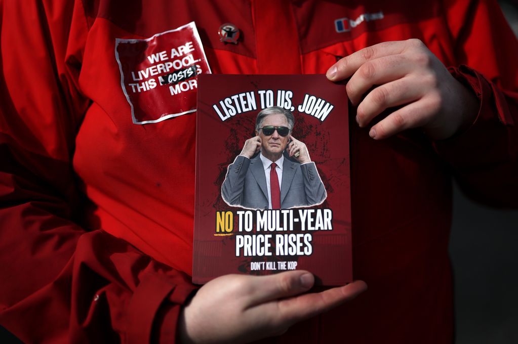 A Liverpool fan holds a sign reading "Listen to us John no to multi-year price rises" 