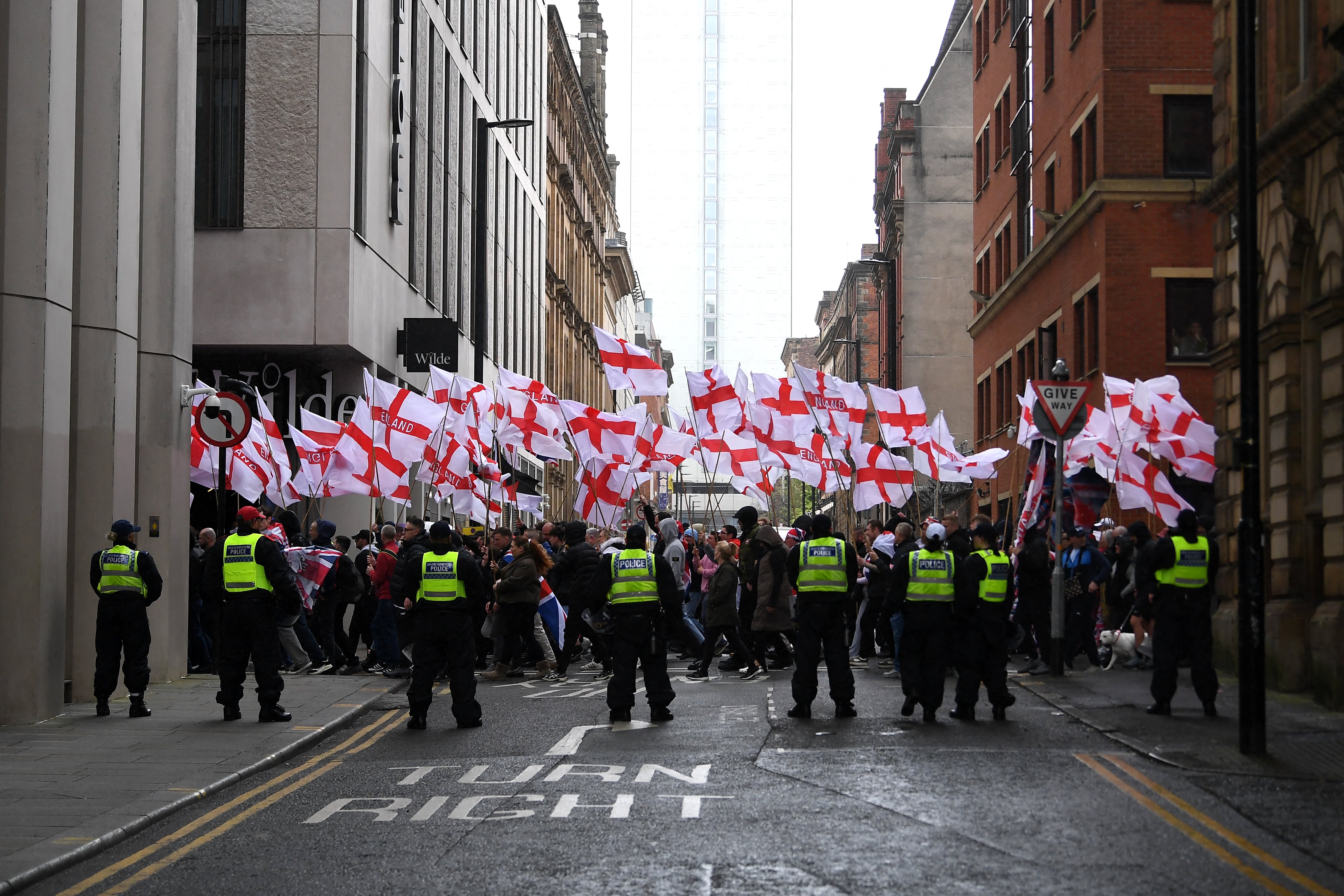 People wave St George's cross flags during a Britain First march in Manchester