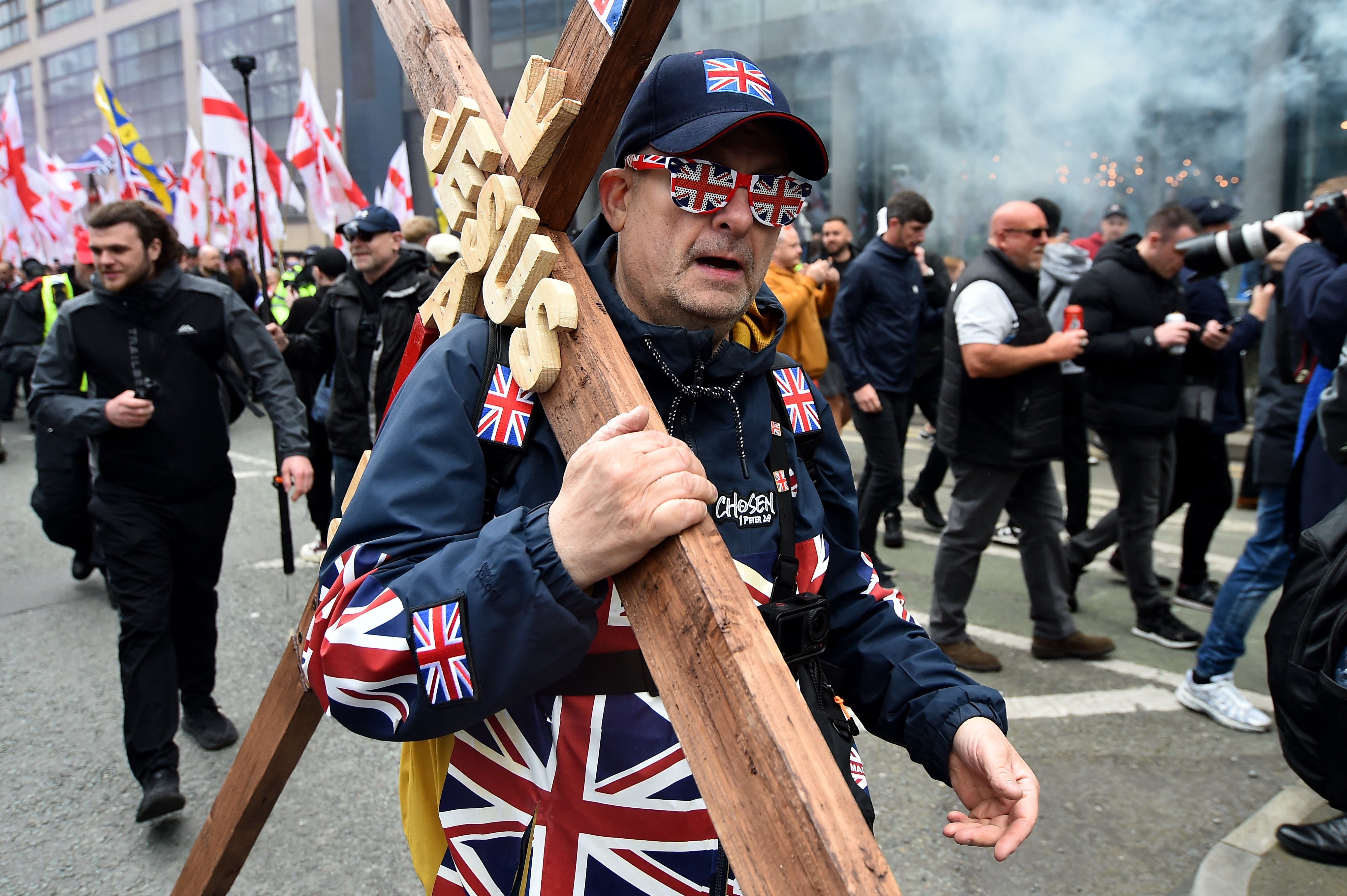 A person carries a large cross during a Britain First march in Manchester on April, 18, 2026.