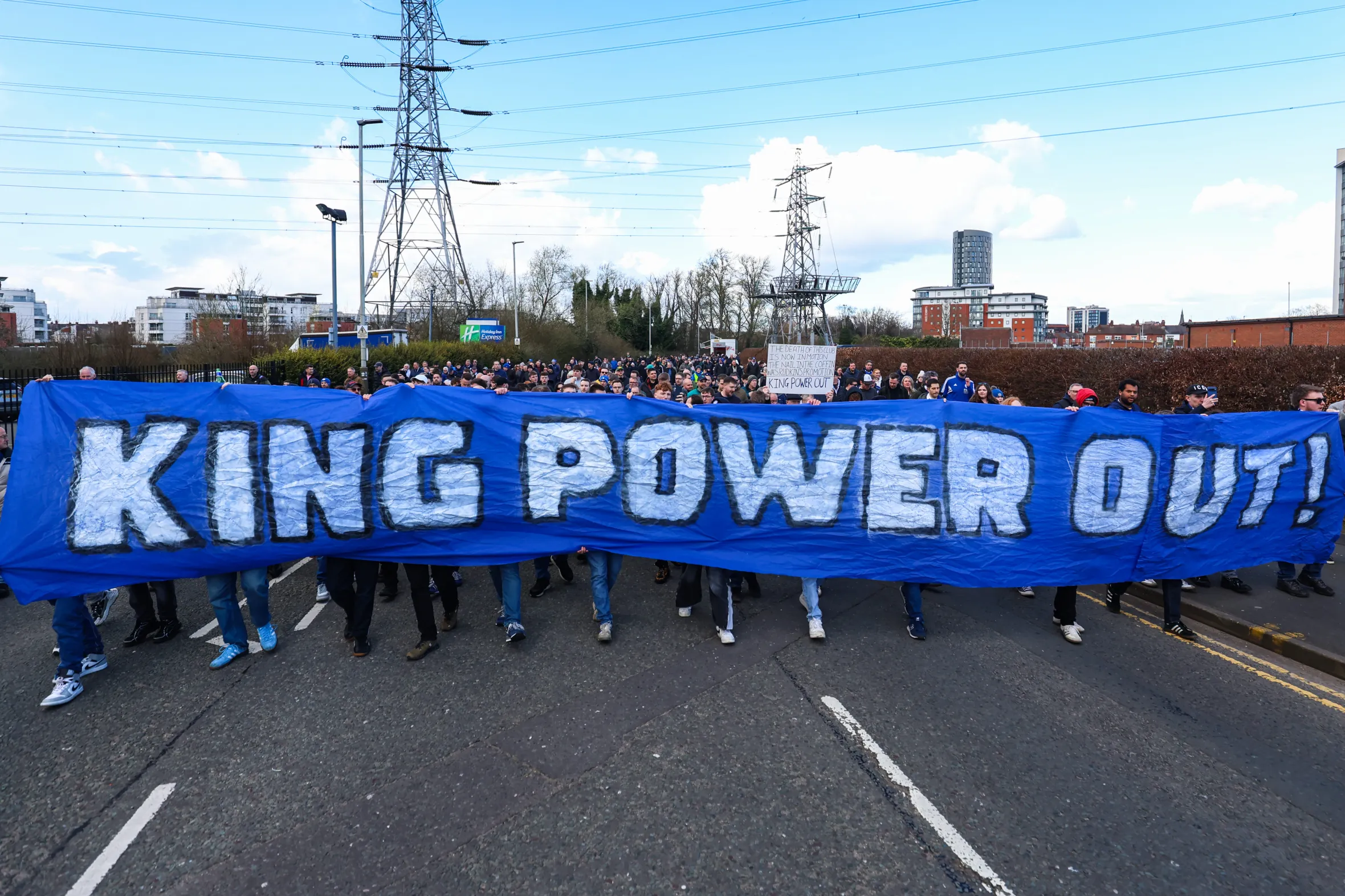Leicester City fans protest with a large blue banner reading "KING POWER OUT!"
