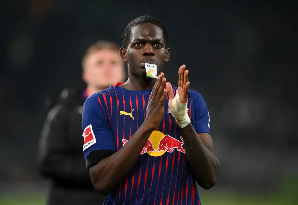 Castello Lukeba applauds the RB Leipzig fans after a match while drinking a sports drink