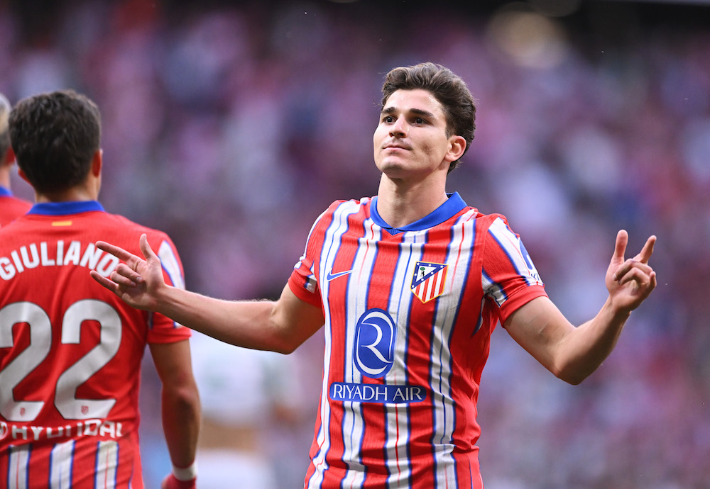 Julian Alvarez in an Atletico Madrid kit stands with his arms spread out after scoring