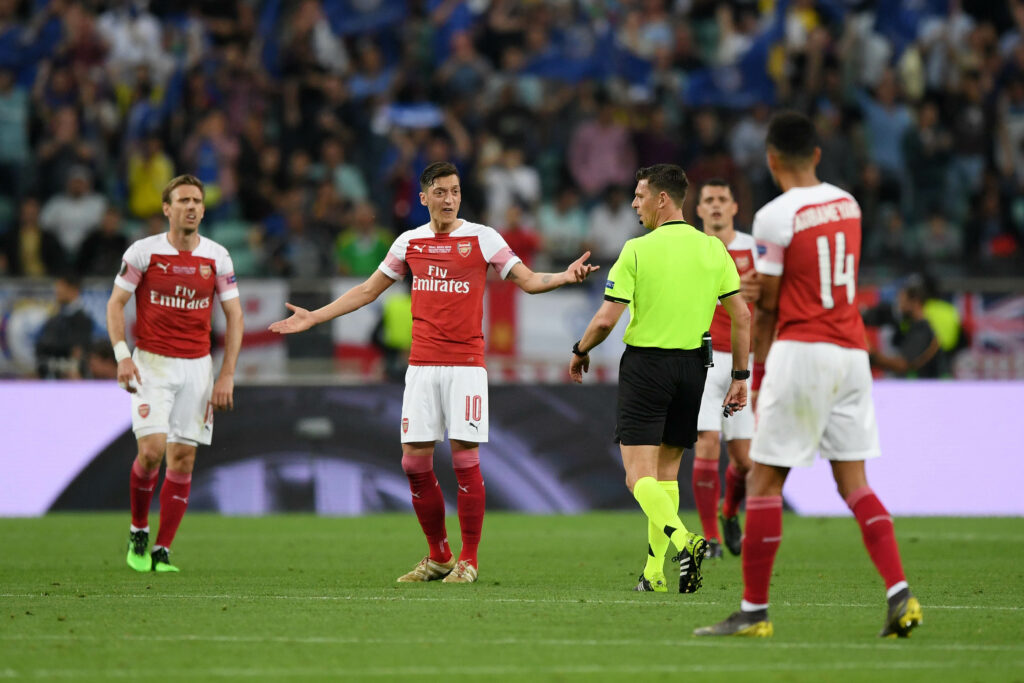 Mesut Ozil, during the Europa League final in 2019 v Chelsea in Baku, gestures with his arms out wide to the referee, Gianluca Rocchi as Nacho Monreal watched on