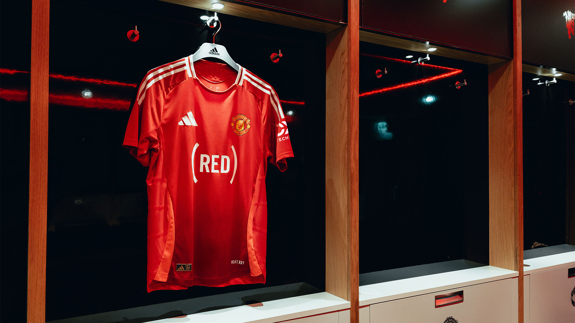 A Manchester United shirt bearing the (RED) Logo hanging in the dressing room at Old Trafford